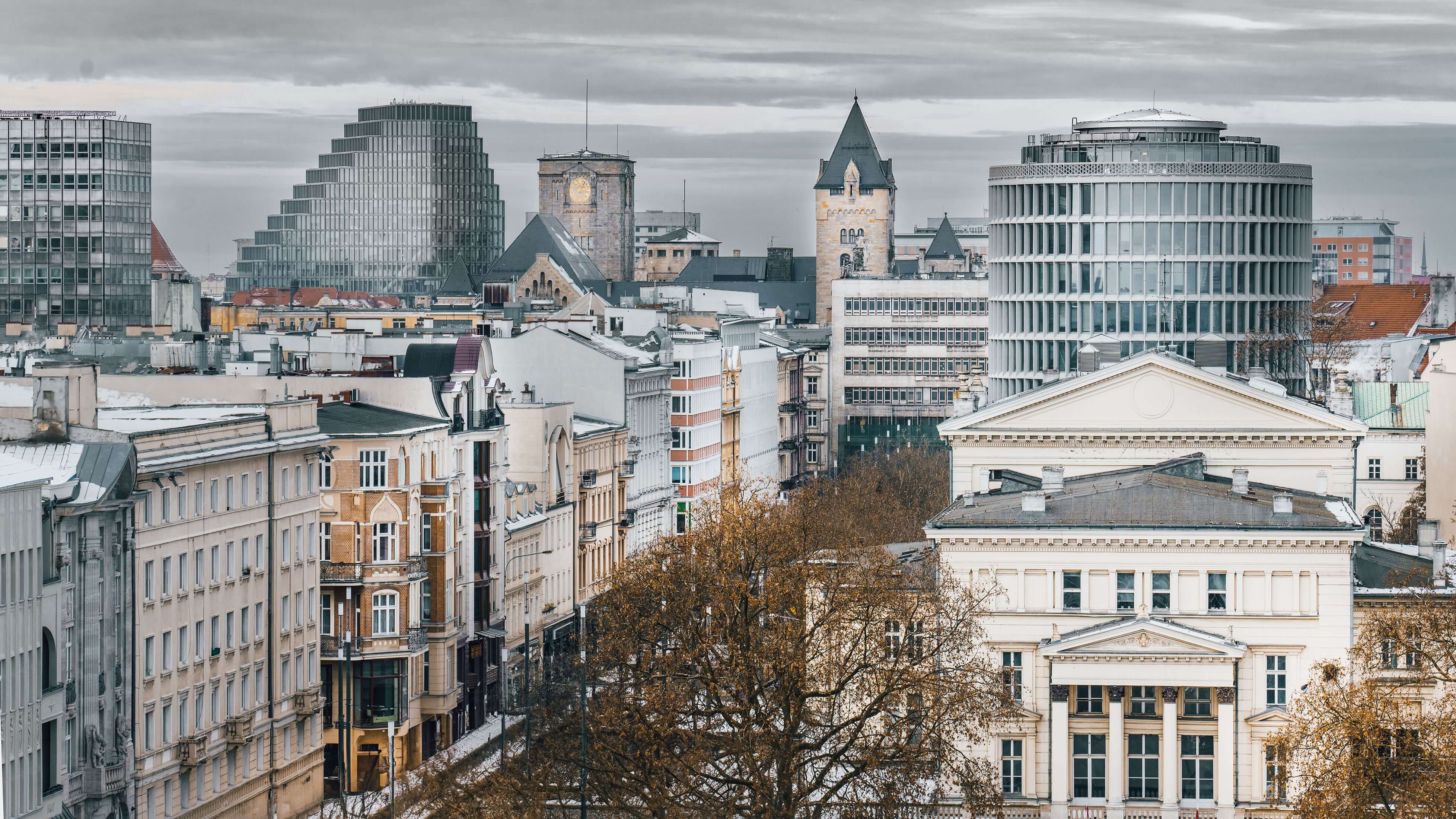Aerial view of a European city skyline in winter, mixing historic and modern buildings under a gray, overcast sky.