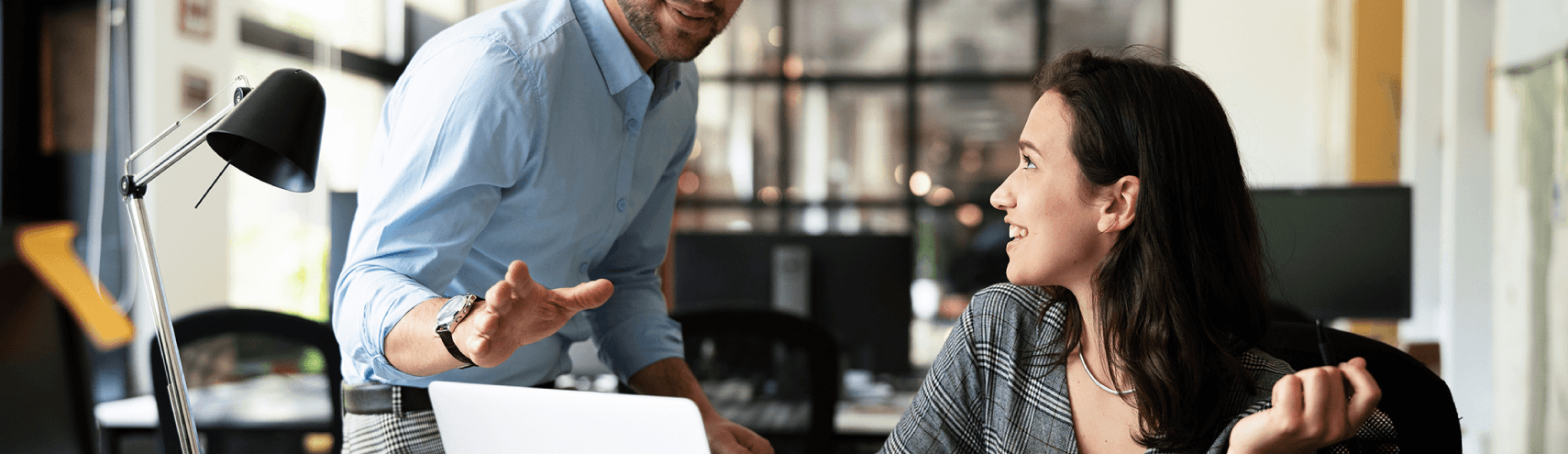 Alation Blog Image: A focus shot of two team members in an office setting as one of them explains to the other what does it mean to make data governance fun.