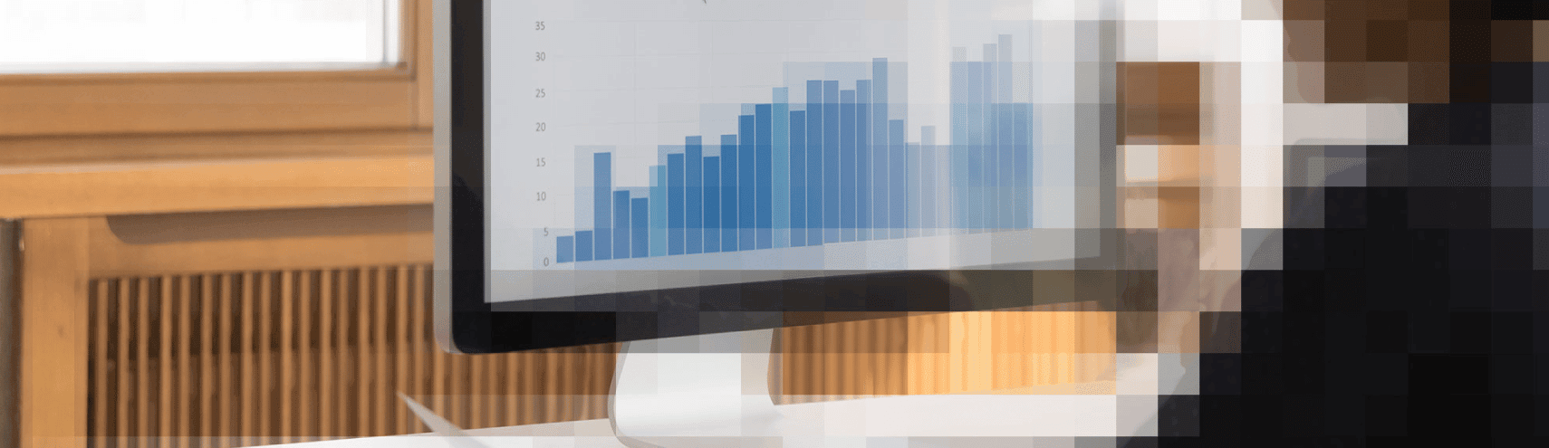 Computer monitor with different bar and pie graphs demonstrating digital transformation as a pixelated person looks through the monitor in an office setting