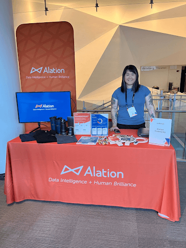 Vibrant snapshot of the Alation booth featuring a cheerful Alationaut