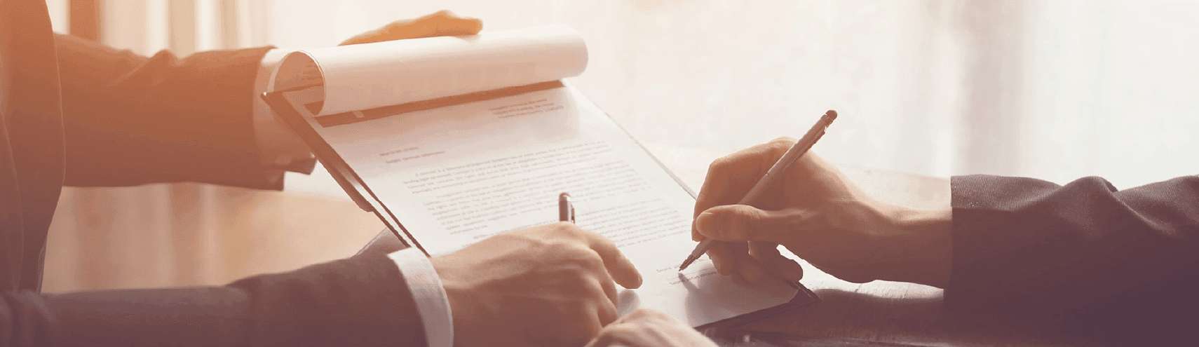 Two hands signing a business contract with pen and paper