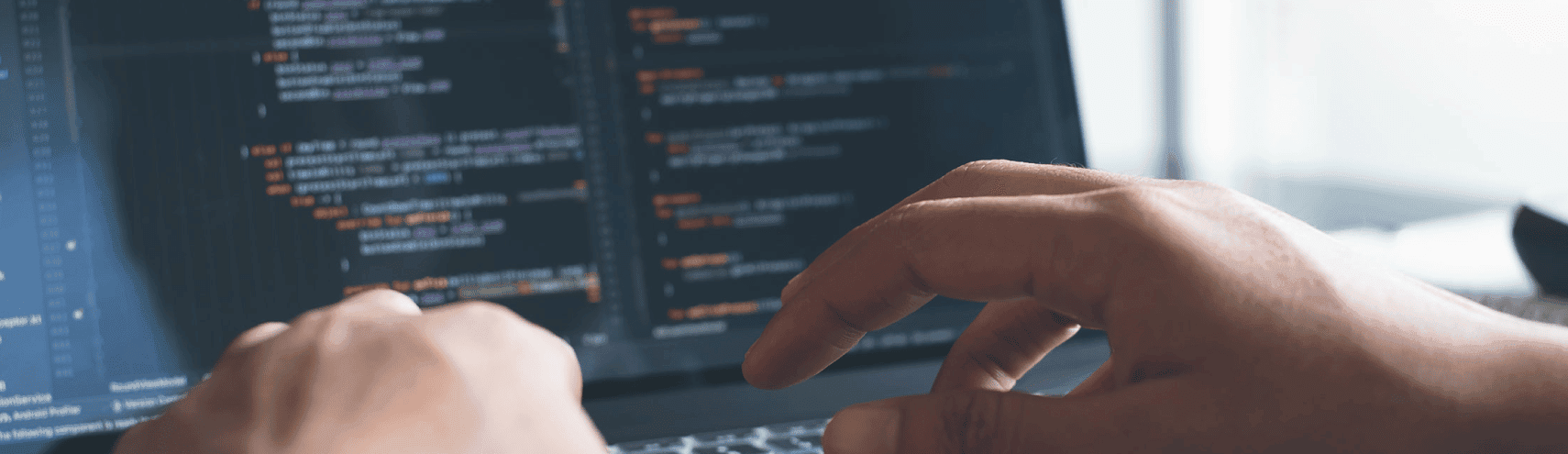 Zoomed up shot of a software engineer's hands coding on their laptop computer