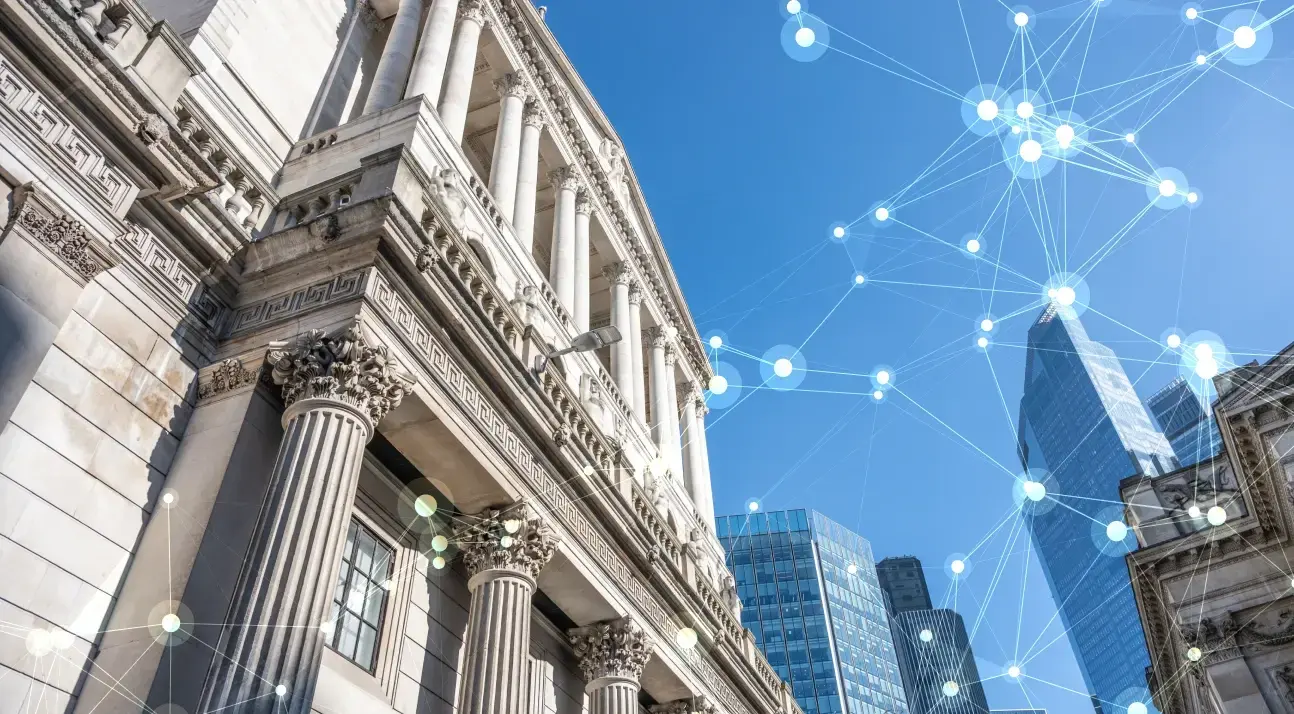 A classical stone building with columns beside modern skyscrapers under a blue sky, overlaid with a glowing digital network graphic.