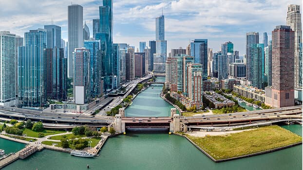 Aerial view of Chicago skyline with tall skyscrapers surrounding the Chicago River and its bridges on a clear day.