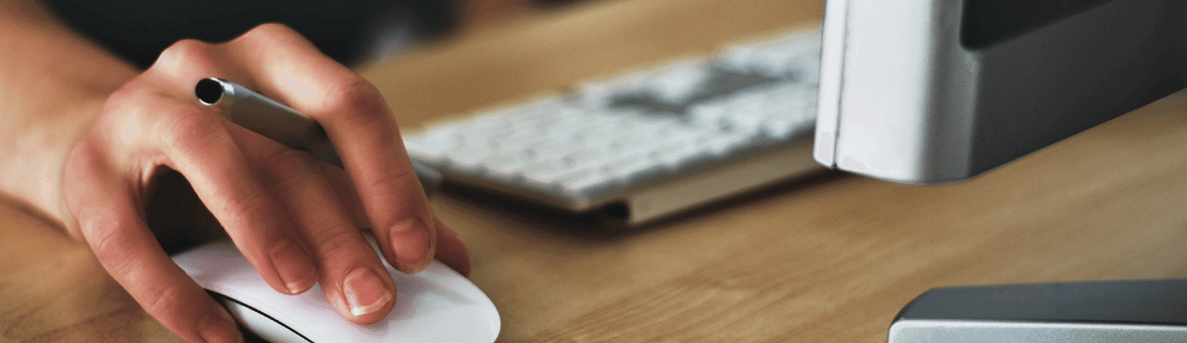 A hand over a mousepad while holding a pen in-between fingers