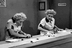 Scene from “I Love Lucy” where Lucy and Ethel are working in a kitchen line gathering all the chocolates and stuffing them inside their blouse.