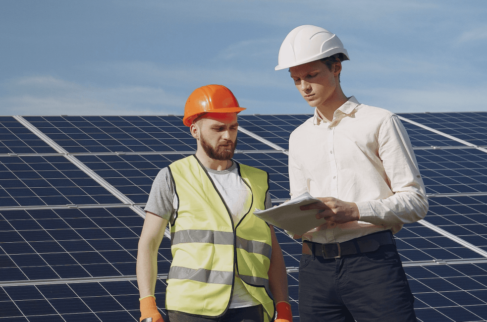 A foreman and businessman at a solar energy station. They are engaged in a discussion.