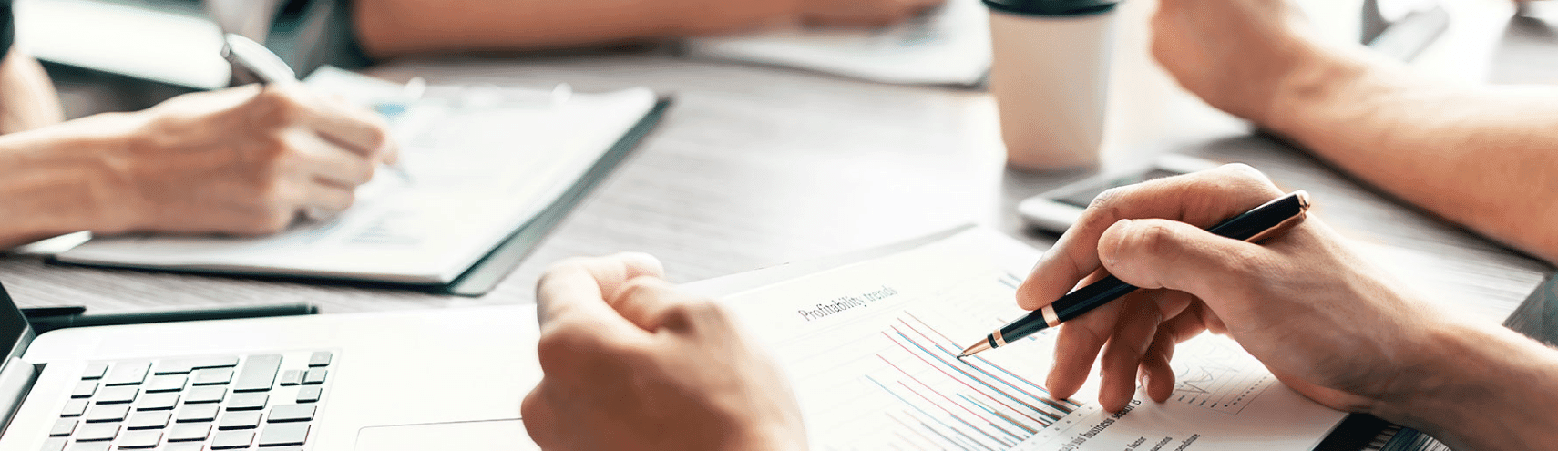 Bird's-eye view of multiple working hands on top of a business desk going over data governance adoption