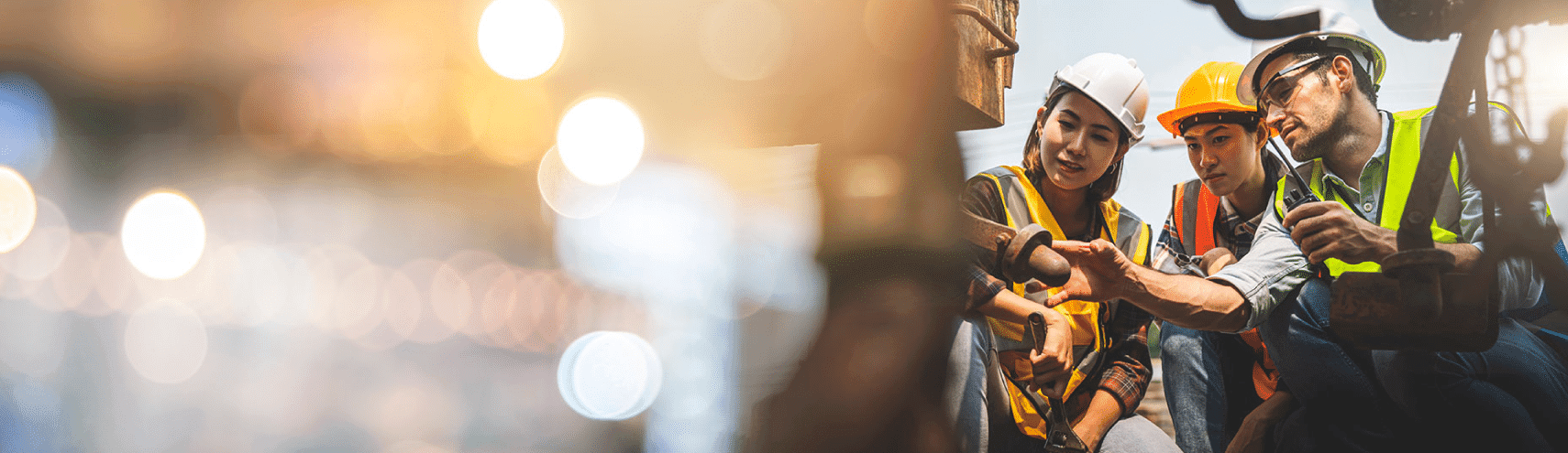 Three construction workers wearing hard-hats checking out a piece of manufacturing equipment