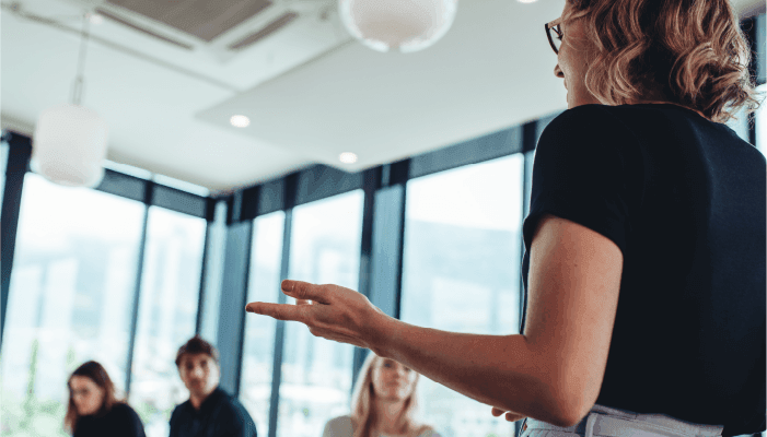 Alation Blog image: A woman presenting to a group in an office