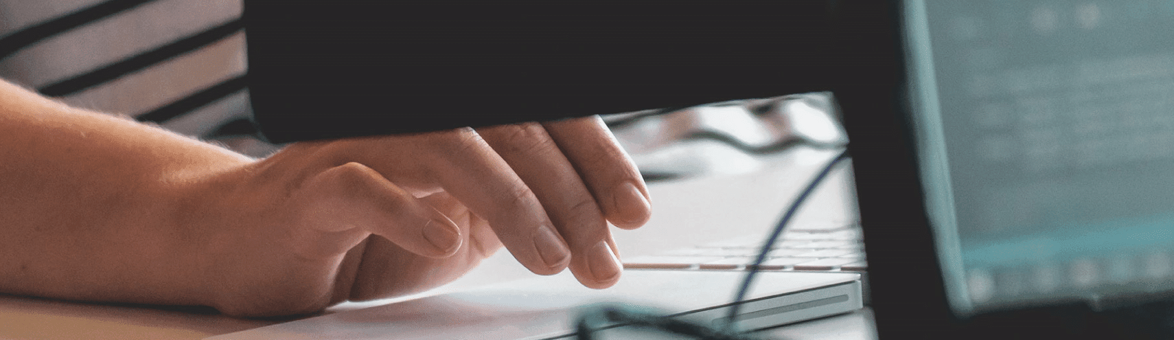 A lower view of someone typing in front of her desktop monitor