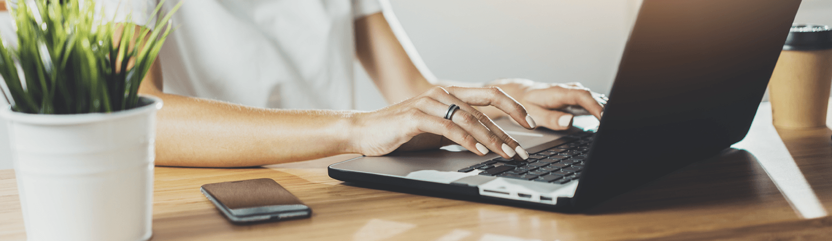 Focus shot of an opened laptop with someone typing on their home work-desk