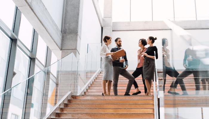 Alation blog image: Four business people standing and talking on the stairs