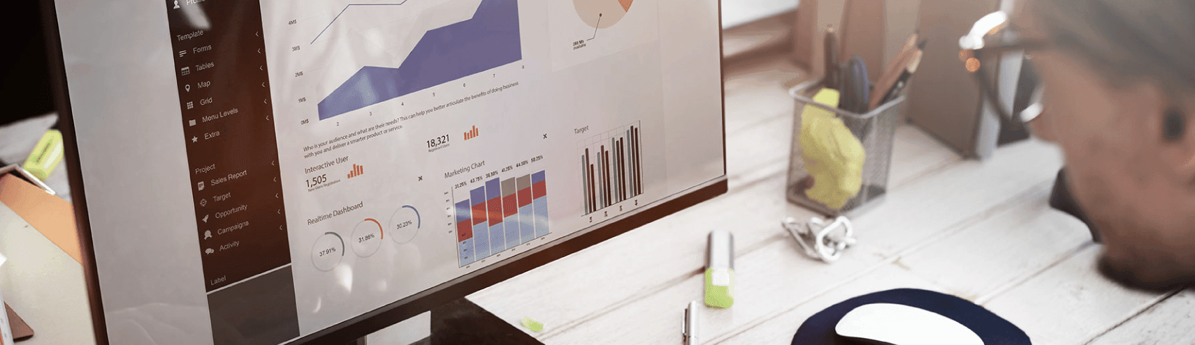 Male business man in an office setting looking through different metrics on his work computer