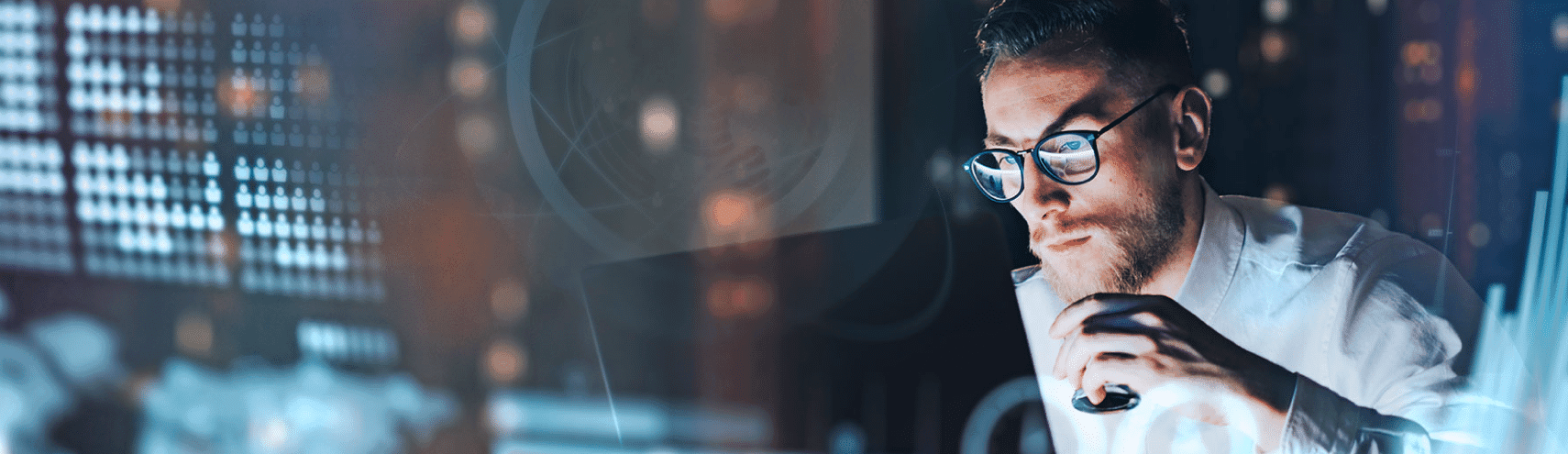 A focused shot of a Business Analyst drinking coffee in an office setting while researching self-service bi vs traditional bi on his desktop computer