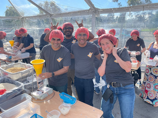 Group of Alationauts joined together and setting up meals to support Rise Against Hunger